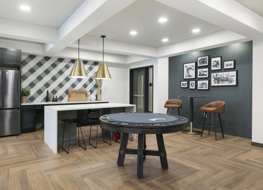 a living room with a round table and a kitchen with a refrigerator