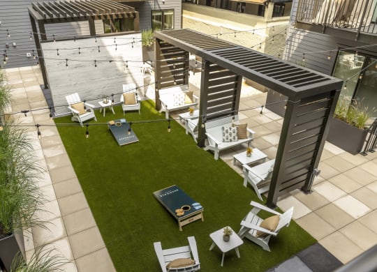 a rooftop patio with tables and chairs and a lawn