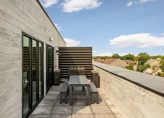 A modern balcony with a table and chairs overlooking a residential area.
