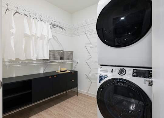 A washing machine is in a laundry room with a dryer in the background.