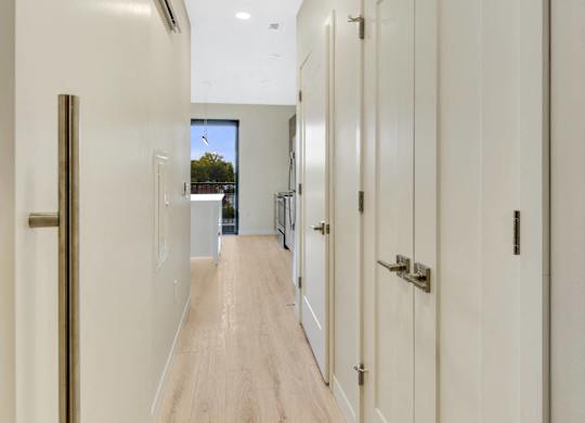 A long hallway with white doors and wood floors.