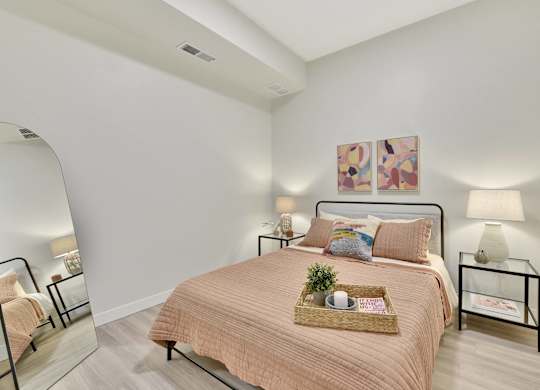 A bedroom with a bed, nightstand, and two wall lamps.