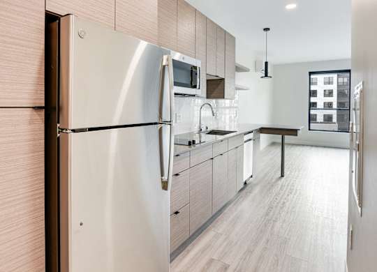 A modern kitchen with a stainless steel refrigerator and wooden cabinets.