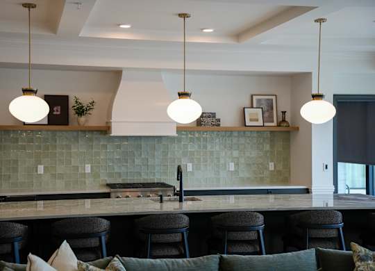 A kitchen with a green tile backsplash and a dark wood counter.