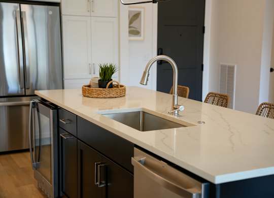 A kitchen with a marble countertop and stainless steel appliances.