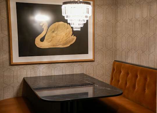 A picture of a swan is hanging on a wall above a table.