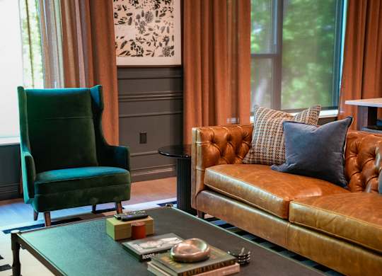 A living room with a green chair and a brown couch.
