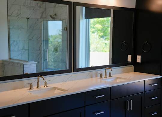 A bathroom with two sinks and a large mirror.