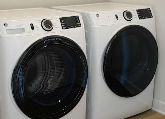 Two white front load washing machines in a laundry room.