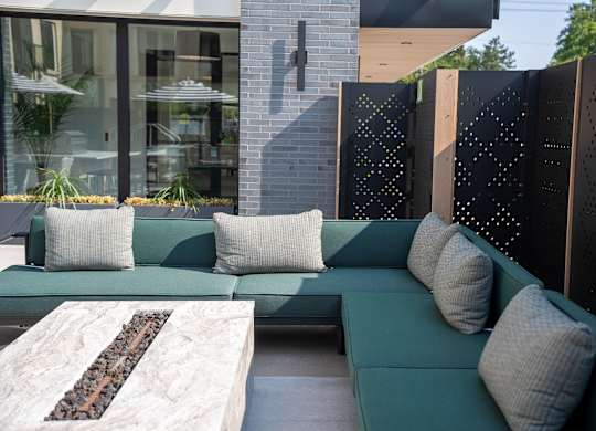 A modern outdoor seating area with a green couch and a stone coffee table.