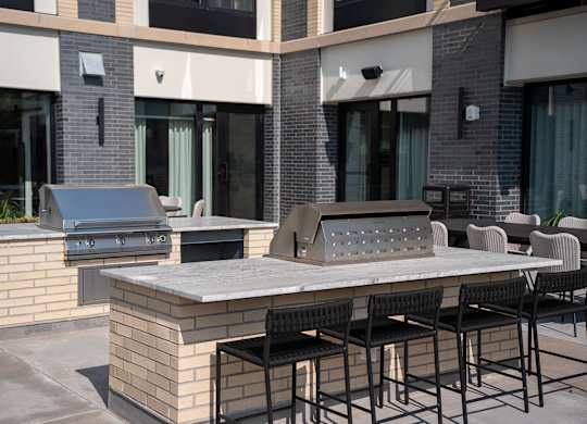 A patio with a table, chairs, and a grill.