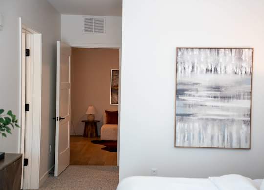 A living room with a white couch and a painting on the wall.