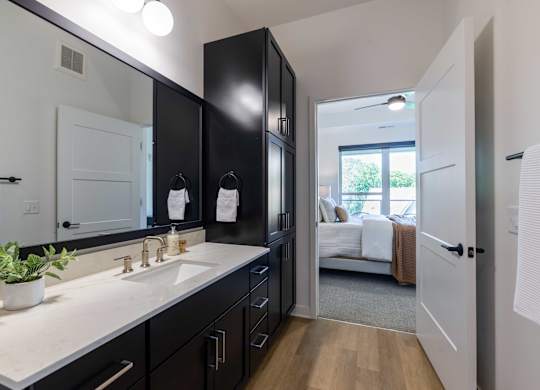 A bathroom with a white counter top and black cabinets.