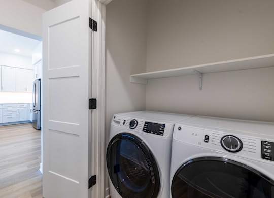 A white door is open to a laundry room with a washer and dryer.