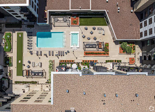 A rooftop patio with a pool and a table with chairs.