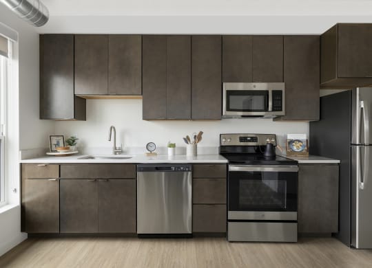 a kitchen with dark cabinets and stainless steel appliances