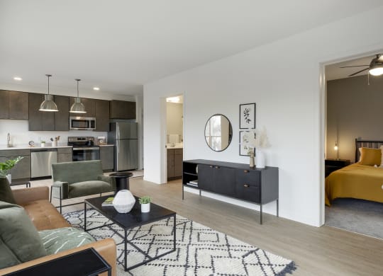a spacious living room with a kitchenette and bedroom in the background