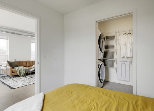 a bedroom with a bed and a closet with a washer and dryer