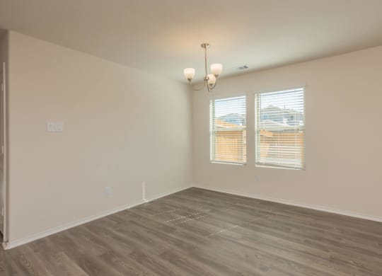 a bedroom with hardwood floors and two windows at The Village at Granger Pines, Conroe