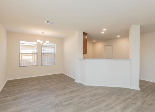 an empty living room with a kitchen in the background at The Village at Granger Pines, Conroe Texas
