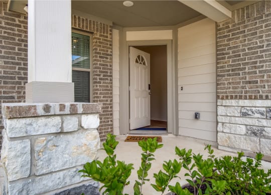 a home entryway with a white door and brick walls at The Village at Granger Pines, Texas