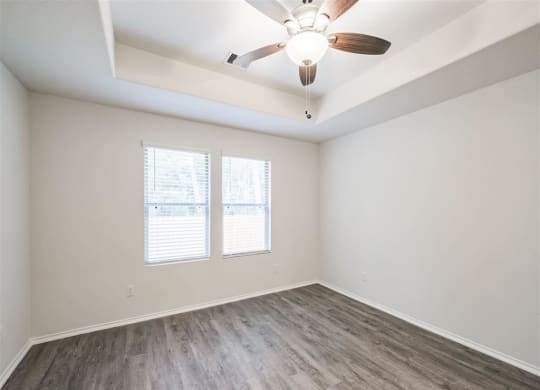 a bedroom with a ceiling fan and two windows at The Village at Granger Pines, Conroe, 77302