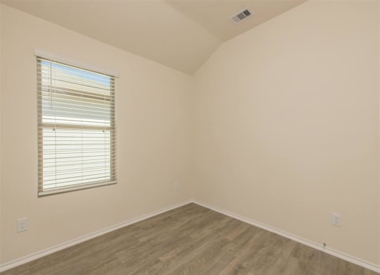 a bedroom with white walls and a window with a blind at The Village at Granger Pines, Conroe
