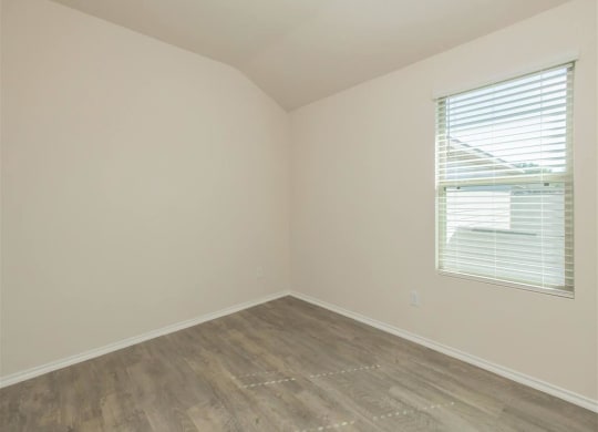 an empty room with a window and a wooden floor at The Village at Granger Pines, Texas