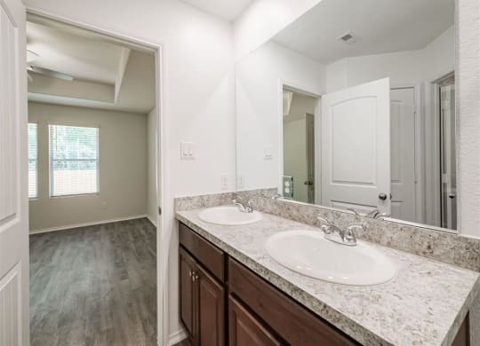 a bathroom with two sinks and a mirror at The Village at Granger Pines, Texas