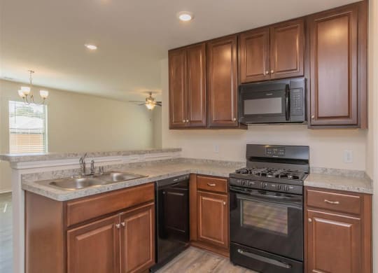 a kitchen with a stove top oven next to a sink at The Village at Granger Pines, Conroe Texas