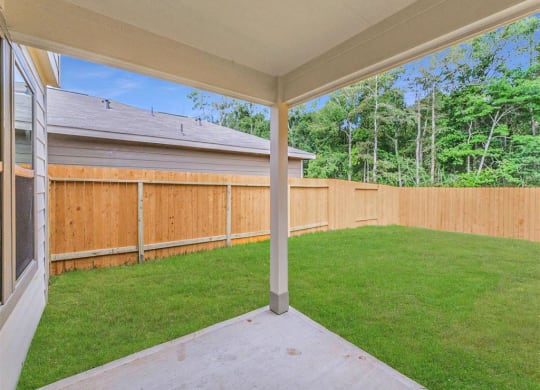 the backyard of a home with a wooden fence and green grass at The Village at Granger Pines, Conroe