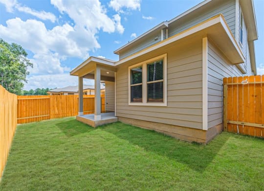 a house with a wooden fence and a green lawn at The Village at Granger Pines, Texas