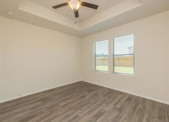 an empty room with a ceiling fan and two windows at The Village at Granger Pines, Texas, 77302