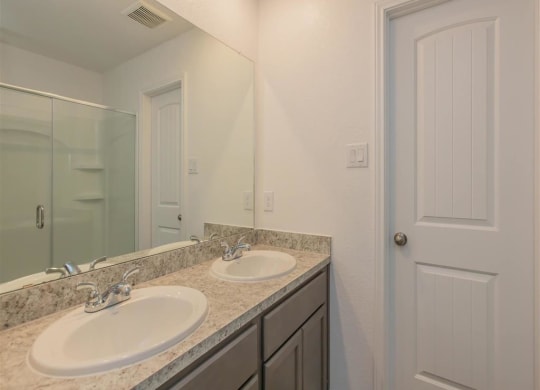 a bathroom with two sinks and a mirror at The Village at Granger Pines, Conroe Texas