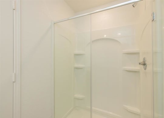 a walk in shower in a bathroom with a glass door at The Village at Granger Pines, Conroe, 77302