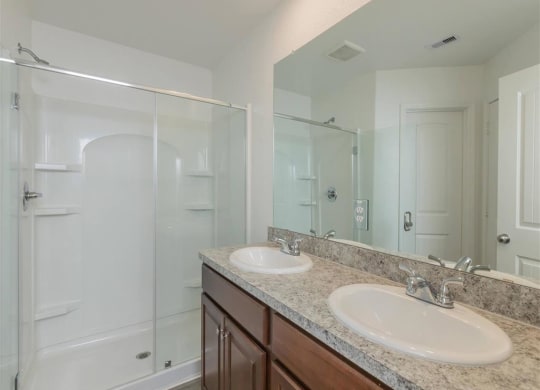 a bathroom with two sinks and a shower at The Village at Granger Pines, Conroe, TX