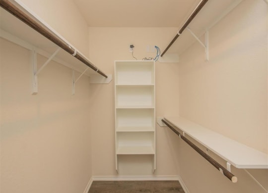 a walk in closet with empty shelves and a bench at The Village at Granger Pines, Texas