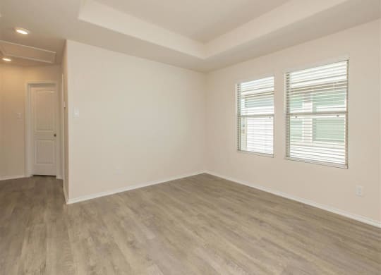 an empty room with a door and three windows at The Village at Granger Pines, Texas, 77302