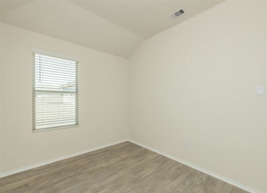 an empty room with a window and a wooden floor at The Village at Granger Pines, Conroe, TX