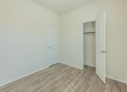 a bedroom with white walls and a wooden floor at The Village at Granger Pines, Texas, 77302