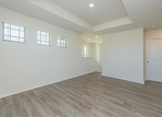 an empty living room with white walls and wood floors at The Village at Granger Pines, Conroe