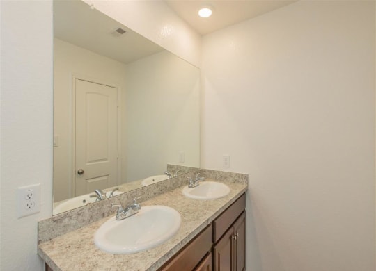 a bathroom with two sinks and a mirror at The Village at Granger Pines, Conroe Texas