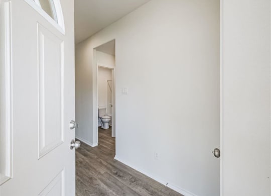 a bedroom with a white door and a bathroom in the background at The Village at Granger Pines, Conroe, 77302