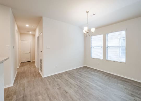 an empty room with a chandelier and three windows at The Village at Granger Pines, Conroe