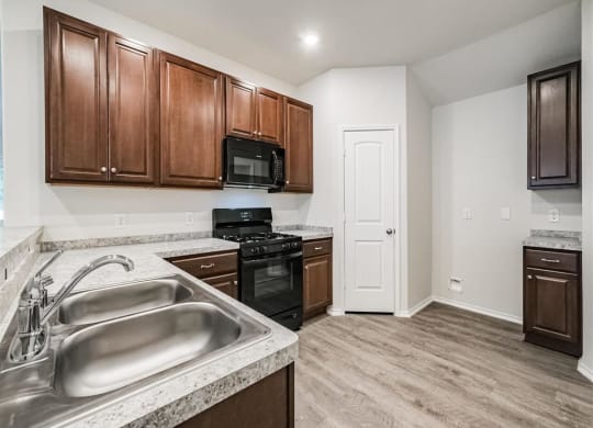 a kitchen with wooden cabinets and a stainless steel sink  at The Village at Granger Pines, Conroe, 77302