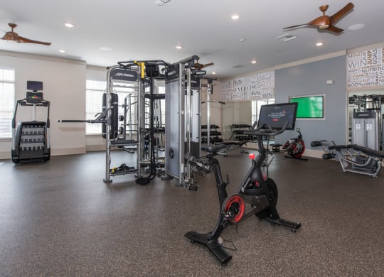 a spacious fitness room with cardio equipment and a large screen tv at The Whitworth, Williamsburg, Virginia