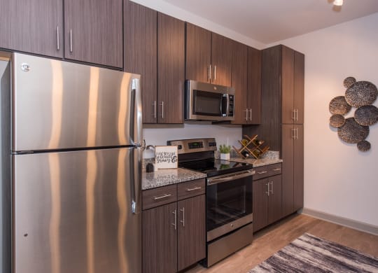 a kitchen with dark wood cabinets and stainless steel appliances at The Whitworth, Virginia, 23185