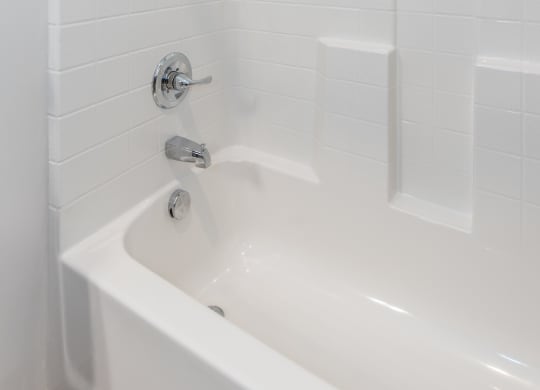 a bathroom with white tile and a white bathtub at The Whitworth, Virginia, 23185