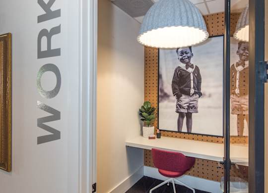 a room with a desk and a lamp and a picture on the wall