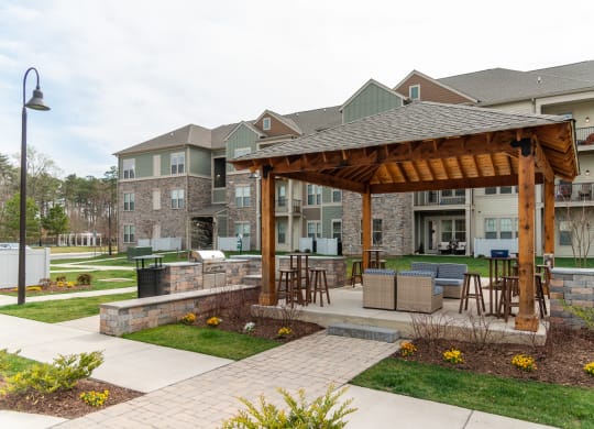 a large wooden pavilion with a stone wall in front of an apartment complex at The Whitworth, Williamsburg, VA
